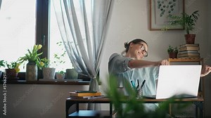 Young adult caucasian woman fooling around and dancing in front of her laptop while working in her home office. Stock Video