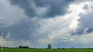 Time lapse big grey clouds moving fast in the sky, green field, grass pitch