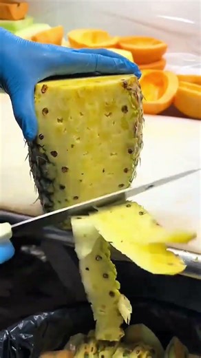 Efficiently Peeling a Large Pineapple with a Sharp Knife on a Cutting Board