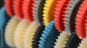 Diagonal view of a row with colorful gear wheels in motion
