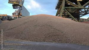 A grain storage facility with piles of grain on the ground. Loading/unloading