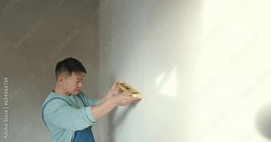 Male worker checking level of the wall with the bubble level tool