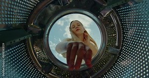 Teenage girl taking washed clothes out of the washing machine, sky with clouds in the background Stock Video