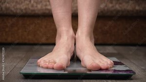 Woman on scales measure weight of close up. Human barefoot measuring body fat overweight. Women legs step scale. Diet female feet standing weighing