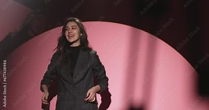 Backstage professional fashion photo shoot. Professional model at work. Young stylish model girl in light of white cyclorama easily and confidently demonstrates necessary poses and emotions