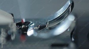 Sewing machine in slow motion. Closeup. Part of sewing machine at textile factory. Sewing needle working. Textile industry. Sewing machine slow motion. Manufacturing equipment at textile factory