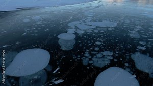 Methane Bubbles Frozen In Surface Of Arctic Circle Lake Ice - Tilt Up. Climate change raises bubbling methane CH4 gas under an Arctic circle lake's solid surface due to permafrost melting.