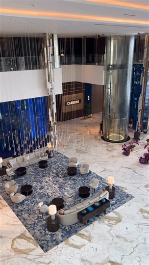 Luxury Travel Expert on Instagram: "World’s most jaw-dropping hotel lobby? Atlantis The Royal in Dubai might just take the crown! Walking in feels like stepping into another dimension—where architecture, art, and luxury collide. Design Highlights: • A soaring, cathedral-like atrium wrapped in warm golden tones • Sculptural column formations inspired by water and fire—Atlantis’ signature elements • Massive geometric screens that filter light like a modern desert mashrabiya • Mirrored surfaces and