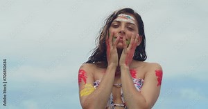 A girl wearing body paint and a bikini enjoys the sun on a white sand beach in the Caribbean facial close up