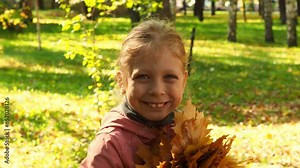 Autumn Portrait of a happy little girl with an autumn bouquet in the park. Beautiful smiling girl against the background of an autumn forest. Happy child in the forest on a walk.