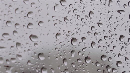 Extreme closeup of large raindrops on window with grey background | Premium Stock Video Footage
