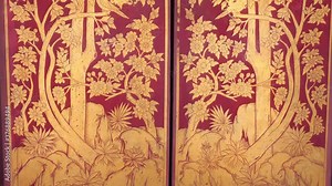 Thai murals depicting traditional flower patterns on a door at Wat Phra Kaew temple.