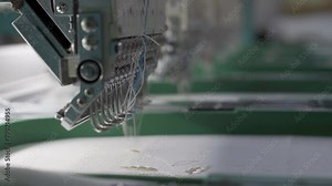 The working process of an industrial sewing machine for applying patterns to a fabric surface.