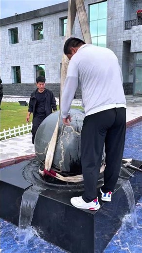 Witness the massive granite water globe being perfectly installed.