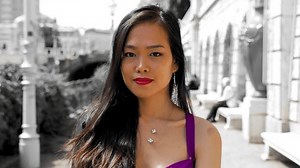 Young Asian woman walking towards camera, hidden indicated smile, purple dress, black and whtie background. Close up, slowmotion.