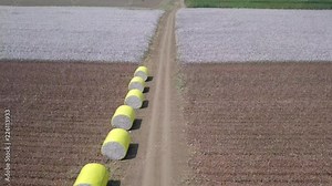 Aerial footage of a vast Cotton field showing both pre and post harvest, with cotton bales wrapped in yellow plastic wraps.