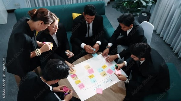 Top view of business people making scrum task board to manage workflow in workplace. Diverse marketing team drawing a line and use colorful stick notes to work on kanban. Creative office. Directorate.