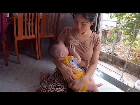 Mom Thuy is breastfeeding at home as daily routine for baby while she is doing cooking...