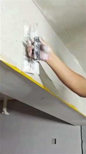 Applying fiberglass mesh tape on ceiling corners for crack prevention