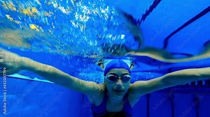 Under water view of professional female swimmer . Underwater footage of woman jumping into water . Swimmer jumping in big swimming large pool. Woman swimmer dive in water pool . Slow Motion .