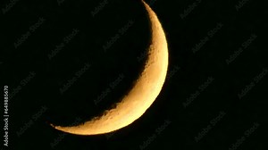 Dark night sky and orange and yellow crescent moon with visible fragments of craters - natural view before moonset in real time. Topics: astronomy, optical phenomenon, atmosphere, cosmos, science