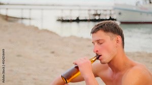 Male gay couple shirtless having fun drinking beer at tropical beach near pier during vacation. Slow motion.