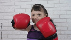 Child in boxing gloves. Aggressive little girl in boxing gloves is working out a blow.