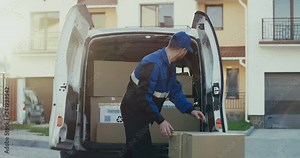 Handsome Caucasian male worker of the shipping company taking out carton parcels from the van.Outside.self isolation, shipping, transportation, quarantine,online, pandemic, food, package