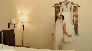 Morning bride. amazing bride comes to wedding dress in bright lights and tries it on, she looks satisfied. Close up slow motion. Young woman bride comes to wear put on wedding dress. Girl arms, veil