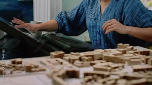 Close up of architectural desk with building model and computer with touch screen. Architect using technology to design maquette for construction development project. Architecture planning