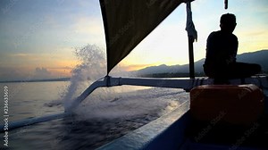 Male riding Outrigger canoe at speed racing across open ocean surface water Bali Indonesia South East Asia