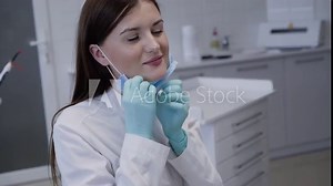 Pretty dentist wears medical mask before consulting patient in dental clinic
