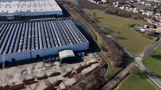 Large industrial warehouses positioned beside SS10 Strada Padana Inferiore within the Pianura Padana near the Po River in northern Italy surrounded by agricultural fields illustrating logistics