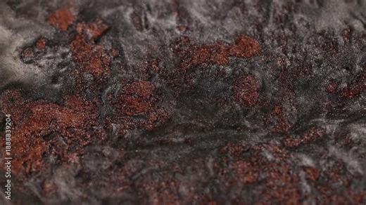 Viscous close-up of black steel paint bubbling and churning slowly revealing deep ridges of shimmering copper particles and forming a cratered lava-like surface on dark background