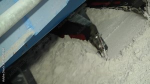 Side scraper reclaimer. Mountains of white sand in the hangar. Works stationary belt conveyor. Bridge scraper with primary and secondary boom for indoor warehouses.