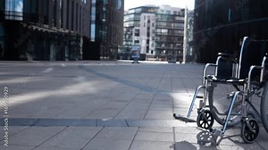 Cripple wheelchair rolling near modern building. Sunset or sunrise. Imminent illness concept. Disease. Slow motion rapidly high framerate camera.