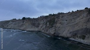 Aerial northern California Point Arena pier cliff sunset. bay surrounded by the Pacific Ocean and coastal mountains. Recreation commercial fishing pier and marina. Scenic and historic buildings.