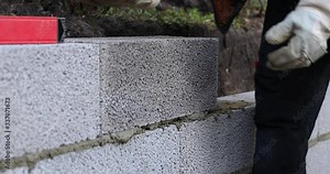 mason working with ceramsite concrete blocks, building retaining wall