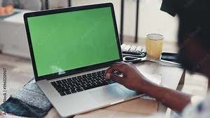 Over shoulder shot of Afro-American male hands using laptop with green screen in a comfortable, light room. Modern devices, social networks, freelancer. Programming. Slow motion, close up view