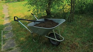 garden cart with earth and a shovel stands on the lawn