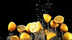 Pieces of juicy lemons with splashes of water fly up and fall down. On a black background. Filmed is slow motion 1000 fps.