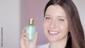 Woman with healthy glowing skin showing natural skincare cosmetic product, face, neck and body tonic lotion bottle, makeup remover and cleanser as luxury skin care and beauty cosmetics commercial.
