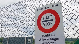 Stop sign on the Airport fence and landing slow motion airplane behind