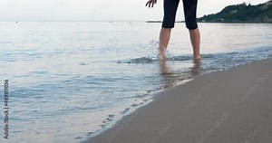 Alone stroll on bare feet. A little girl stroll along the sea line on the wet sand.