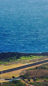 High angle establishing shot of Kalaupapa airport and small plane landing on the island of Molokai, Hawaii.