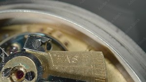 Moving gold gears inside working pocket watch mechanism. Working clock mechanism with rotating spring, gears, gearing and toothed wheels. Inside view of a moving clockwork. Macro shot. Rack focus.