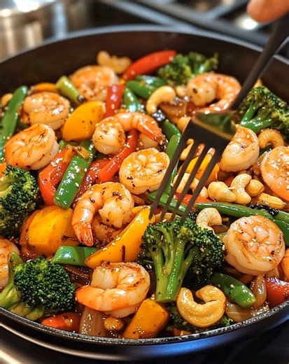Garlic Shrimp Stir-Fry with Cashews 🍤🥦 Colorful, crunchy, and saucy — the perfect quick weeknight dinner! 📝 Ingredients: 1 lb large shrimp, peeled and deveined 2 tbsp olive oil 3 garlic cloves, minced 1 tbsp soy sauce 2 tbsp oyster sauce 1 tbsp honey 1 tsp sesame oil 1 red bell pepper, chopped 1 yellow bell pepper, chopped 1 cup broccoli florets ½ cup snap peas ¼ cup roasted cashews Salt and black pepper, to taste 1 tbsp chopped green onions or parsley (for garnish) 🍴 How to prepare it: 1️⃣ 