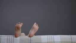 Having fun child feet close up playful legs kid on bed dancing. Pair...