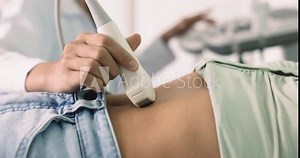 Female pass abdominal or gynecological ultrasound examination in clinic, close up. Sonographer or ultrasound technician check patient internal organs using convex probe and ultrasonography equipment