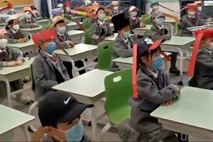 Students in China wear social distancing hats